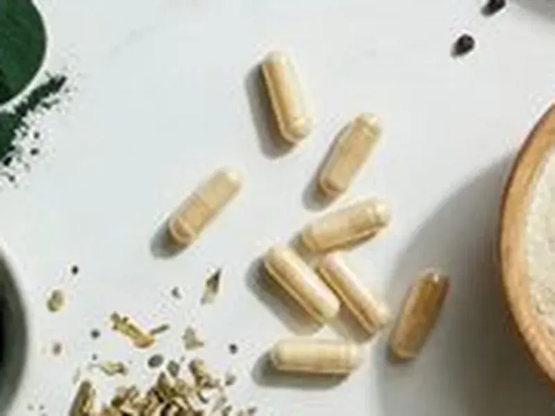 Tan supplement capsules on a white surface